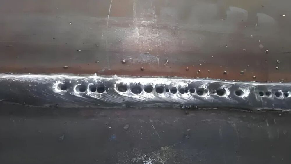 金属表面带有多个孔洞的特写图像，展示工业质检中可能存在的产品缺陷，体现Qwen3-VL模型的视觉缺陷识别能力