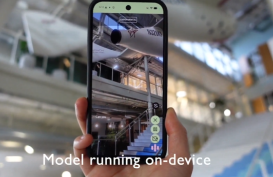 一只手握着智能手机，屏幕显示模型运行界面，下方文字标注“Model running on-device”，体现谷歌Gemma 3 270m模型在移动设备上的本地运行场景，支持图像与文本处理等多模态任务。